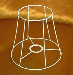 a white wire basket sitting on top of a brown cloth covered floor next to a wall