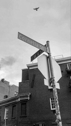 a street sign on top of a stop sign in front of a tall brick building