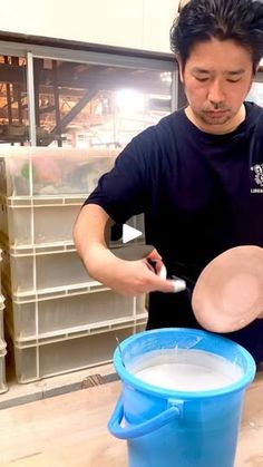 a man is mixing something in a blue bucket