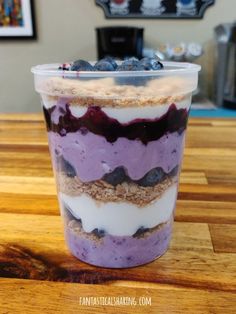 blueberry cheesecake parfait in a plastic cup on a wooden counter top