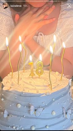 a woman holding a baby in front of a cake with lit candles on it,