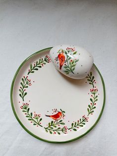 an egg sitting on top of a white plate next to a red and green bird