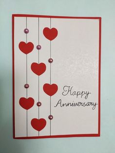 a happy anniversary card with hearts hanging from strings