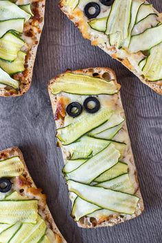 four slices of bread with cucumbers and olives on them