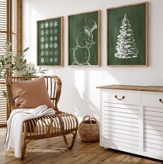 a room with three framed christmas pictures on the wall and a chair in front of it