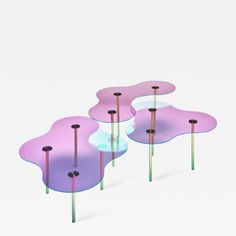 three glass tables with metal poles in the shape of flowers