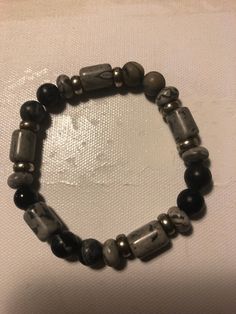 This is a black and gray mix stone bracelet With silver fillers. This looks great on his or her wrist. This item is not as light as a wooden bead around your wrist. But nice around the wrist. Casual Gray Bracelets For Everyday, Casual Silver Bracelets With Gemstone Beads, Casual Silver Stretch Bracelet With Black Beads, Handmade Gray Bracelets For Everyday, Everyday Handmade Gray Bracelets, Casual Gray Bracelet, Casual Gray Beaded Bracelets, Casual Gray Beaded Bracelets As Gift, Casual Gray Handmade Bracelet