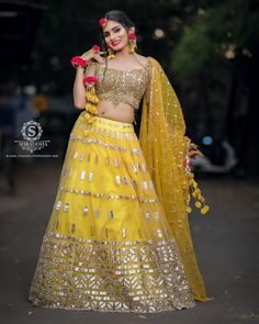 a woman in a yellow lehenga and matching dupatta is posing for the camera