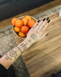 a woman's hand with hendix on it next to a bowl of oranges