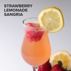 a close up of a drink in a glass with strawberries and lemons on the side