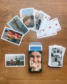 several playing cards are laid out on a wooden table, including one with a cell phone