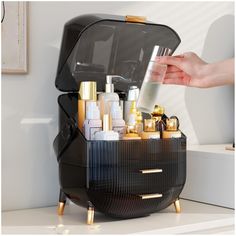 a person is holding a bottle in front of a black case with gold trimmings