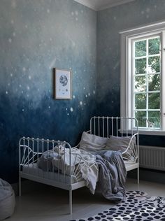 a small white bed sitting in a bedroom next to a window with stars painted on the wall