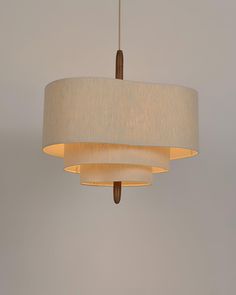 a white lamp hanging from a ceiling with a beige shade on the top and bottom