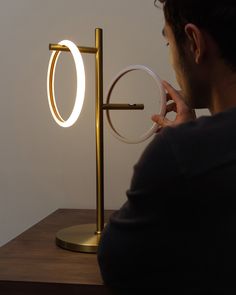 a man looking at an illuminated ring on a table top with a magnifying glass in front of him