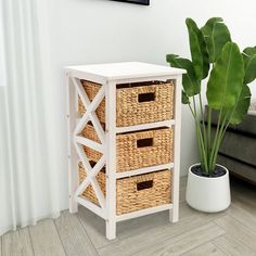 a white table with three wicker baskets on it next to a potted plant