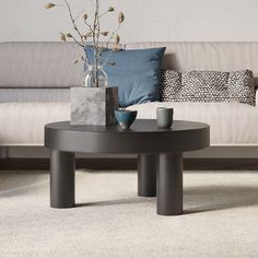 a coffee table with vases on it sitting in front of a couch and pillows