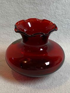 a red glass vase sitting on top of a white tableclothed flooring area