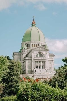 a large white building with a green dome on it's top surrounded by trees