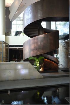 a large spiral staircase in the middle of a building next to a pool with water