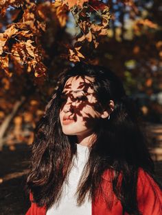 a woman standing under a tree with leaves on it's head and her eyes closed