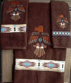 three towels with native designs on them sitting on a towel rack next to a mirror