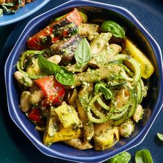 a bowl filled with pasta and veggies on top of a blue tablecloth