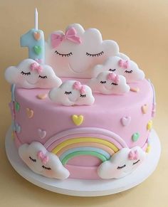 a pink cake with white clouds and rainbows