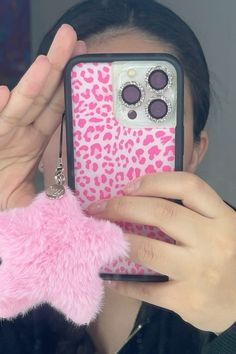 a woman holding up a pink phone case with a stuffed animal in front of her