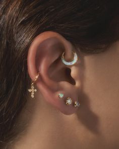 a close up of a person wearing ear piercings with pearls and stars on them