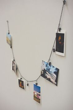 several pictures hanging on a chain attached to a wall