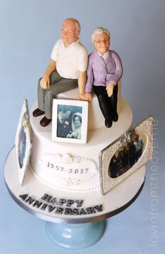 two figurines sitting on top of a cake with an anniversary photo and frame