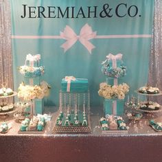 a table topped with cakes and cupcakes under a blue sign that says jeremah & co