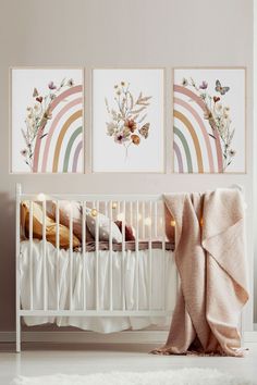 a baby's crib with three pictures hanging on the wall and a blanket draped over it