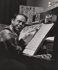 a black and white photo of a man sitting in front of a drawing easel