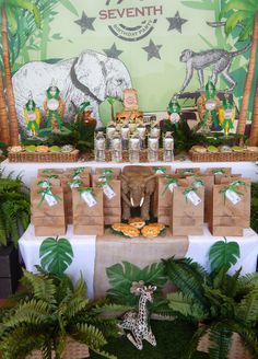 an elephant themed birthday party is set up on a table with jungle decorations and desserts