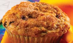 a muffin sitting on top of a yellow napkin next to a rainbow colored cloth