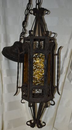 an old fashioned light hanging from the ceiling in a room with white walls and curtains