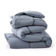 a stack of pillows and blankets on top of each other in grey color, with the covers folded down