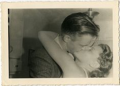 an old black and white photo of a woman kissing a child