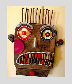 a wooden mask with many different colored eyes and hair clips on it's head