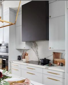 a kitchen with marble counter tops and gold accents on the cabinets, along with white cupboards