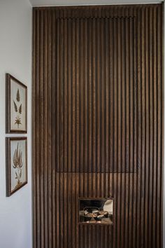 a wooden paneled wall in the corner of a room with two framed pictures on it