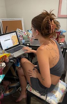 a woman sitting in front of a laptop computer on top of a desk next to a chair