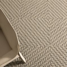 a white chair sitting on top of a floor next to a carpet covered in grey herringies