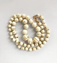 This fun beaded necklace dates from the 1980s and is made from lightweight plastic beads which have been splattered with gold paint. They are separated with tiny gold colour glass seed beads. It measure is 24 inches = 61cm long. There are a couple of tiny spacer beads which have darkened but overall the necklace is in great condition. ALL INTERNATIONAL SHIPPING IS SENT TRACKED & SIGNED WITH JUST ONE FLAT RATE FEE WORTH $10.  NO ADDITIONAL COST FOR EXTRA ITEMS! Acrylic Necklace, Splatter Paint, Vintage Beads Necklace, Paint Effects, Wedding Jewellery Necklace, Plastic Beads, Paint Splatter, Cream And Gold, Beads Necklace