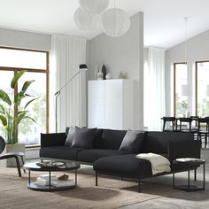 a living room filled with black furniture and large windows next to a dining table on top of a rug