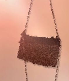 a brown purse hanging from a chain on a wall