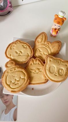 some cookies that are on a plate with pictures and a teddy bear in the background