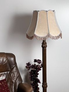 a lamp sitting on top of a wooden table next to a brown leather chair and pillow